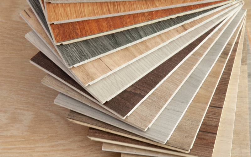 Muestrario abanico de suelos laminados de diferentes tonalidades y texturas de madera, desde claros a oscuros, ideales para asesoramiento en la elección de parquet o tarima flotante para reformas de viviendas.